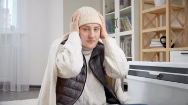 Evde kalın kıyafetler ve şapkalar giymiş donan bir kadının portresi. Enerji krizi, yüksek faturalar, ekonomi ve aylık kamu hizmetleri ödemelerinde tasarruf kavramı