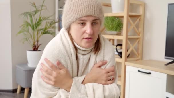 暖かい帽子とセーターの若い女性が自宅で寒さを感じる エネルギー危機 高い手形 経済の概念と毎月の公共料金にお金を節約 — ストック動画