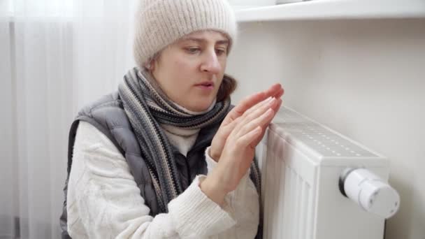 在平整的暖气暖炉前 一个女人试图温暖她冰冷的双手的画像 能源危机概念 高额费用 供热系统中断 节约和节省每月公用事业付款 — 图库视频影像