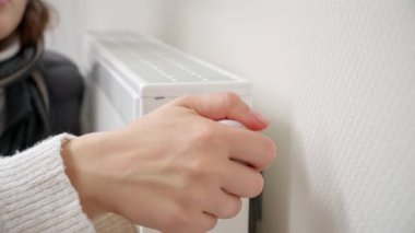 Isıtıcı radyatör termostatını ayarlayan ve ellerini ısıtan kadına yakın çekim. Enerji krizi, yüksek faturalar, bozuk ısıtma sistemi, ekonomi ve aylık kamu hizmetleri ödemelerinde tasarruf kavramı