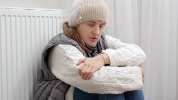 一个心情烦躁的女人坐在家里破了的散热器旁 感觉很冷 能源危机概念 高额费用 供热系统中断 节约和节省每月公用事业付款 — 图库视频影像