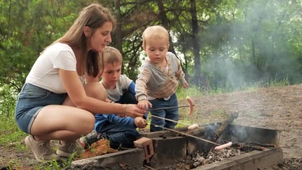 Young Mother Two Sons Cooking Sausages Bonfire Camp Active Leisure — Stock Video