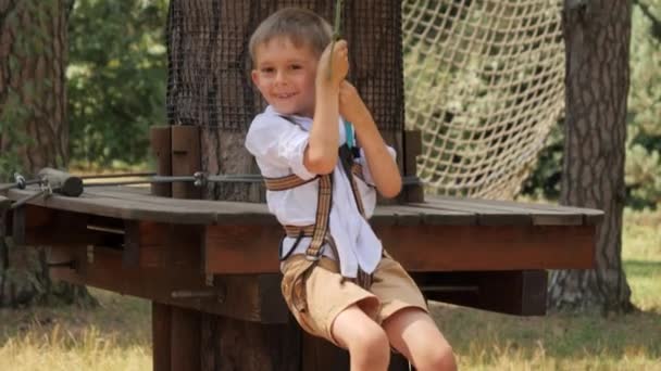 拍下了一个微笑的男孩在冒险公园里玩耍和骑在拉链上的照片 活跃的童年 健康的生活方式 户外玩耍的孩子 大自然中的孩子 — 图库视频影像