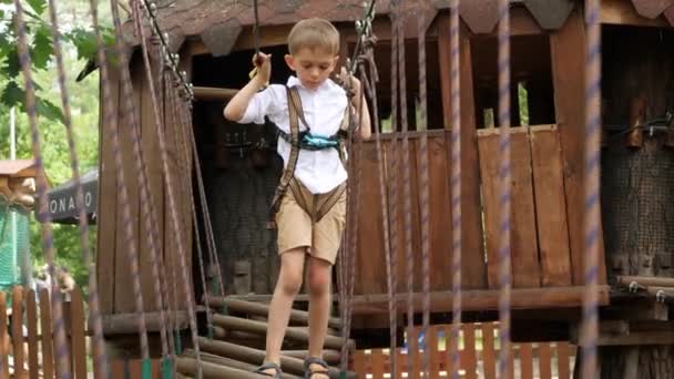Kleiner Junge Hält Sicherungsseil Der Hand Und Überquert Wackelige Brücke — Stockvideo