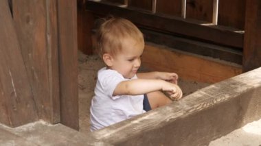 Tahta kum havuzunda oynayan küçük bir çocuğun portresi. Çocuklar dışarıda oynuyor, çocuklar eğleniyor, yaz tatili ve tatil