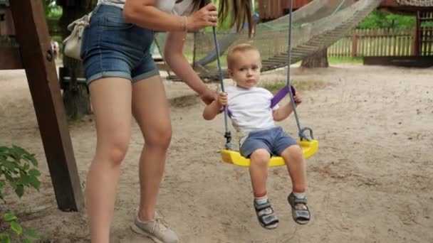 Jovem Mãe Apoiando Segurando Seu Filhinho Balançando Playground Swing Crianças — Vídeo de Stock