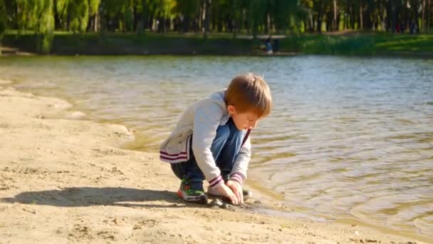 Mały Chłopiec Siedzący Brzegu Rzeki Bawiący Się Mokrym Piaskiem Dzieci — Wideo stockowe