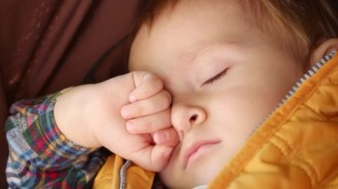 Park 'taki bebek arabasında uyuyan bebeğin yüzünün yakın çekimi. Çocuk gelişimi, çocukların dinlenmesi, bebek sağlığı.