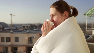 Gülümseyen kadının portresi balkonda dinleniyor ve çay içiyor. Sabahları insanlar evlerinde dinleniyor, şehir manzarasının tadını çıkarıyorlar.