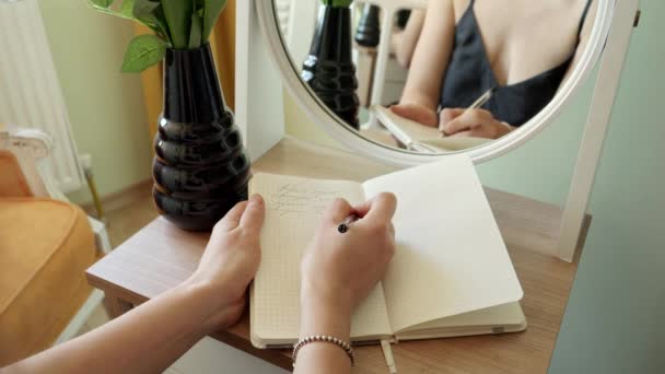 Primer Plano Mujer Escribiendo Cuaderno Mientras Está Sentado Mesa Maquillaje — Vídeos de Stock
