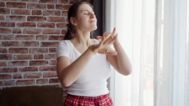 Büyük pencerenin yanında dans eden ve eğlenen güzel bir kadının portresi. İnsanlar evde rahatlıyor, eğleniyor, olumlu duygular ve sevinç yaşıyor.