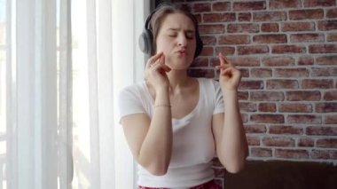 Evde müzik dinleyen ve dans eden mutlu bir kadın. İnsanlar evde rahatlıyor, eğleniyor, olumlu duygular ve sevinç yaşıyor.