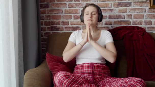 Junge Frau Mit Kopfhörern Meditiert Auf Sofa Wohnzimmer Konzept Der — Stockvideo