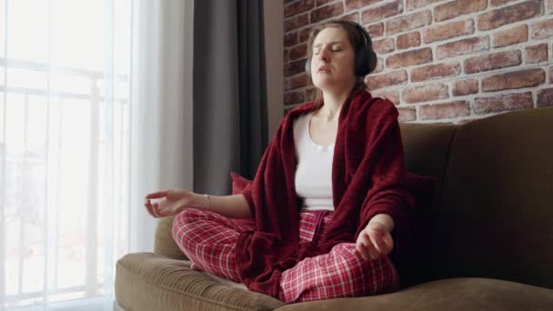 Piękna Kobieta Medytująca Kanapie Słuchająca Mantr Słuchawkach Pojęcie Relaksu Zdrowego — Wideo stockowe