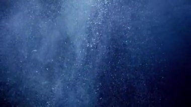 Hava kabarcıkları yüzüyor ve deniz yüzeyine yükseliyor. Güneş ışığı okyanusta parlıyor. Su altı arkaplanı veya arkaplan özeti.