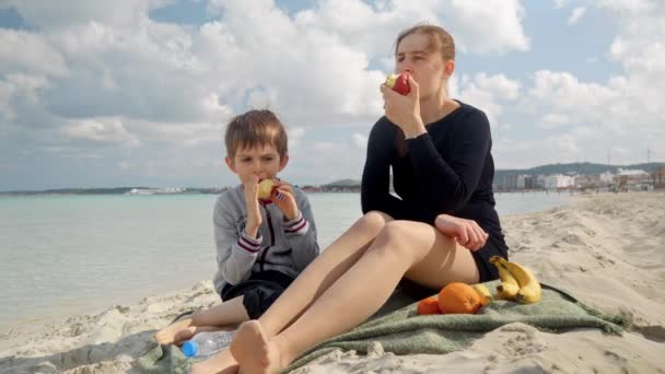 Feliz Menino Sorridente Relaxante Com Mãe Praia Mar Comer Maçãs — Vídeo de Stock