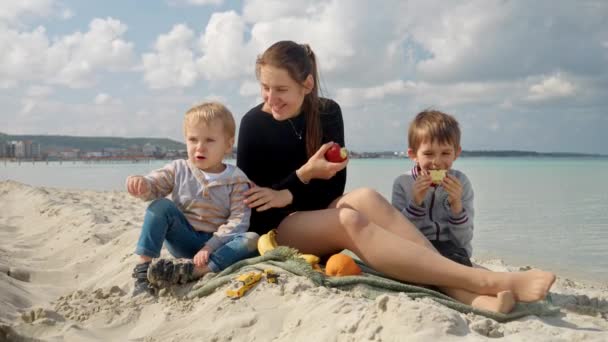 Jovem Com Dois Filhos Fazendo Piquenique Praia Areia Comendo Maçãs — Vídeo de Stock