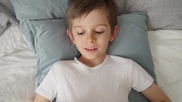 Niño Feliz Acostado Cama Usando Una Tableta Durante Día Niño — Vídeos de Stock