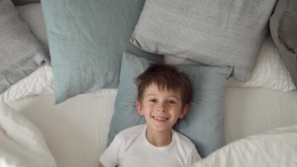 Menino Feliz Deitado Cama Abrindo Seu Cobertor Com Sorriso Dirigido — Vídeo de Stock