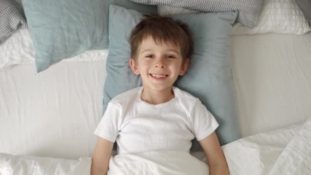 Портрет Счастливого Веселого Мальчика Лежащего Постели Улыбающегося Камеру Положительные Эмоции — стоковое видео