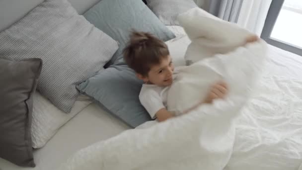 小男孩从毯子下跳了出来 脸上挂着笑容 欢快地笑着 流露出一种无忧无虑的幸福感 — 图库视频影像