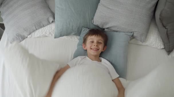 快乐的笑脸男孩打开毛毯 伸出手躺在床上 — 图库视频影像