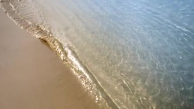 Sakin deniz dalgaları üzerinde uçan yavaş çekim kameraları kumlu sahilde dönüyor..