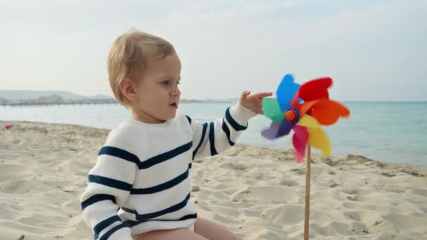 해변의 모래사장에 바람개비를 가지고 귀여운 아이의 방학이나 주말에 자녀의 행복에 — 비디오