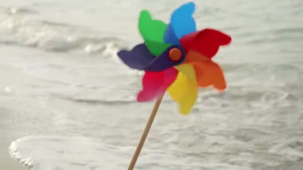 Πολύχρωμο Pinwheel Περιστρέφεται Μια Αμμώδη Παραλία Δίπλα Κυλιόμενα Κύματα Της — Αρχείο Βίντεο