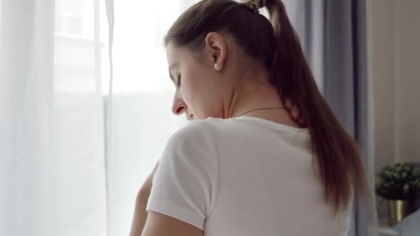 若い女性が寝室に座って 彼女の痛みを伴う首と背中をこすったりマッサージします 医療問題 痛みの軽減と怪我の概念 — ストック動画