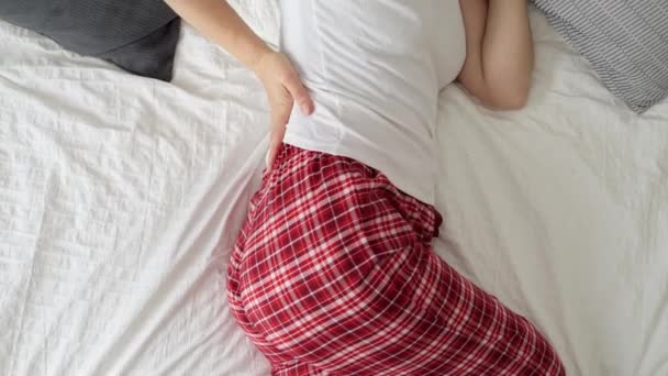 Młoda Kobieta Leżąca Łóżku Piżamie Wyglądająca Zmartwioną Masująca Sobie Plecy — Wideo stockowe