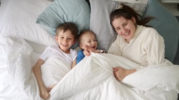 Uma Jovem Mãe Alegre Cama Com Seus Dois Filhos Acenando — Vídeo de Stock