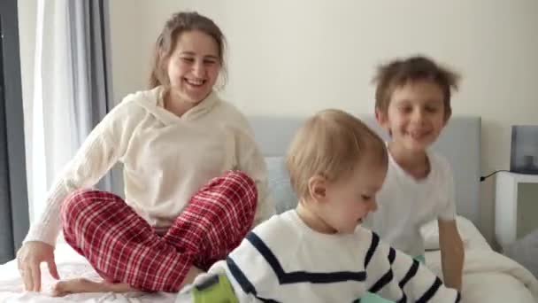 Счастливая Веселая Мать Двумя Сыновьями Пижаме Прыгающими Мягкой Кровати Утрам — стоковое видео