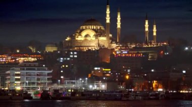 İstanbul, Türkiye - Şubat 2023: Aydınlatılmış Hagia Sofya Camisi ve geceleyin İstanbul Boğazı 'ndaki sakin deniz suyu.