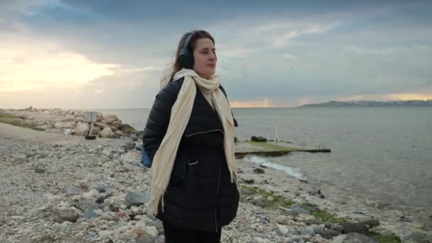 Sırt Çantası Kulaklığıyla Deniz Kıyısında Yürüyen Gülümseyen Bir Kadın Macera — Stok video