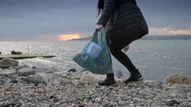 Plaj temizleme kampanyasına katılan genç bir kadın, plastik bir torbada çöp toplama ve çevrenin korunmasına katkıda bulunma