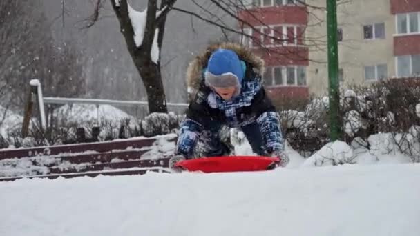 Young Boy Big Smile Slides Snowy Slope His Plastic Sled — Stock Video
