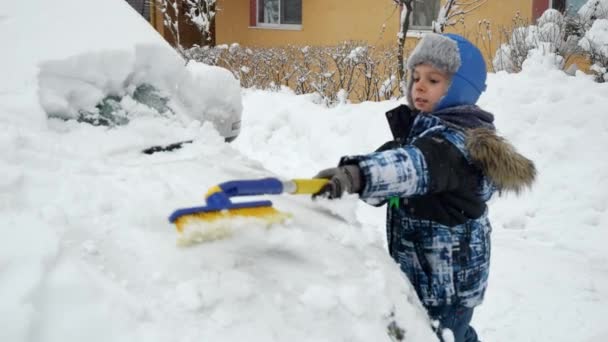 Młody Chłopiec Szczęśliwie Usuwał Śnieg Samochodu Rodziców Szczotką Mroźny Zimowy — Wideo stockowe