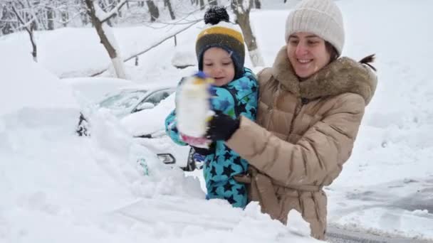 Usmívající Matka Její Syn Čistí Sníh Auta Štětcem Sněhové Bouři — Stock video