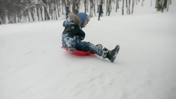 Młody Chłopak Śmieje Się Uśmiecha Zjeżdżając Śnieżnego Wzgórza Skacząc Trampolinie — Wideo stockowe