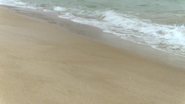 Soğuk bulutlu bir günde kumlu sahilde dalgaların yavaşça dalgalanması. Mevsimlik turizmin sonu, kışın seyahat