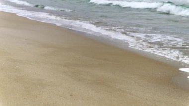 Soğuk bulutlu bir günde terk edilmiş kumlu deniz sahilleri ve dalgalı deniz dalgaları. Mevsimlik turizmin sonu, kışın seyahat