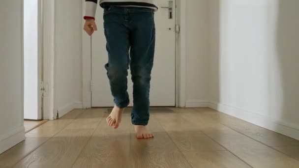 自宅の長い廊下で木製の床に実行されている小さな男の子の足のスローモーション映像 幸せな子供時代の概念 家庭で遊ぶ 子供の発達 — ストック動画