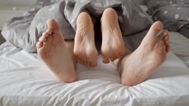 Sevgi dolu çiftlerin ayaklarının sevişmesi, yumuşak bir yatakta battaniyenin altında samimi bir an. Bir ailede sevgi ve sevginin önemini göstermek için mükemmel.