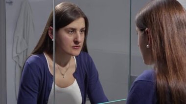 Üzgün, genç, esmer kadın aynada kendine bakıyor. Depresyon, stres, zihinsel hastalık ve sorunlar, yalnızlık ve hüsran kavramı