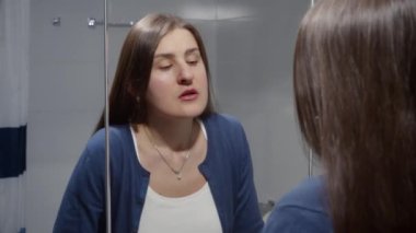 Lavaboda dikilip aynaya bakan genç bir kadın. Depresyon, stres, zihinsel hastalık ve sorunlar, yalnızlık ve hüsran kavramı