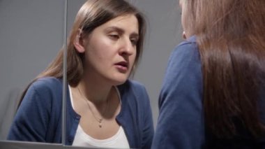 Stresli bir kadın aynada dikilip aynaya bakarken mutsuz olur. Depresyon, stres, zihinsel hastalık ve sorunlar, yalnızlık ve hüsran kavramı