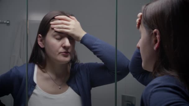 バスルームミラーで彼女の反射を見て動揺ストレスの女性 女性のうつ病や負の感情 — ストック動画