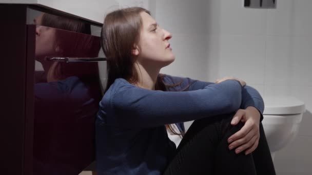 涙の目をした不幸な悲しい女性がバスルームで床に座っている うつ病 家庭内暴力 ストレス フラストレーションの概念 — ストック動画