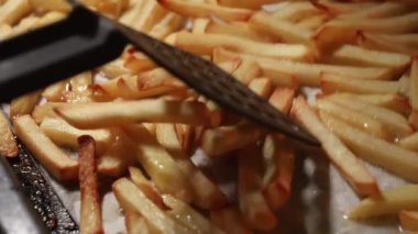 Patates kızartmasını fırında spatulayla karıştırma. Fast food, sağlıklı beslenme, fırında pişirme.